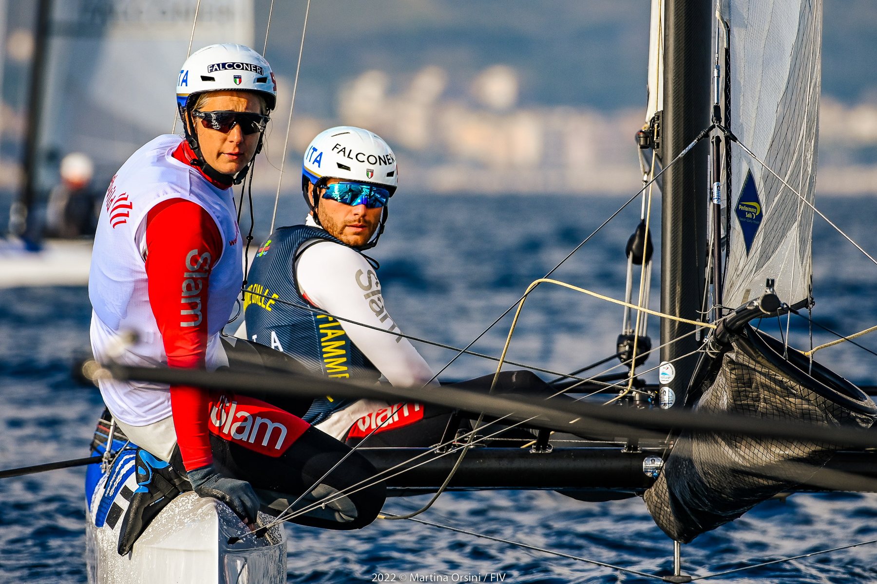 Primo piano di due velisti con casco su un catamarano Nacra 17