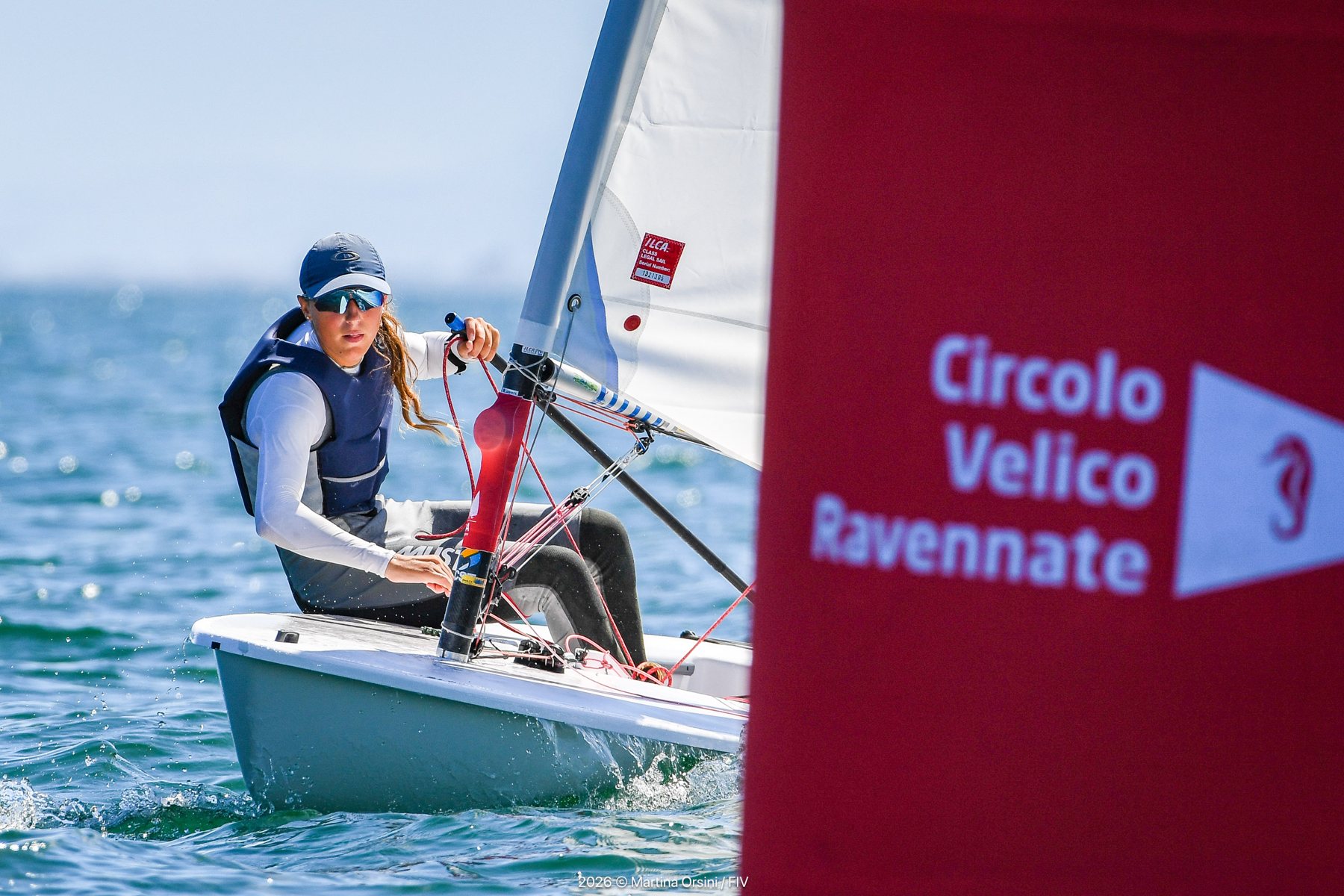 Giovane velista in Optimist accanto a una boa del Circolo Velico Ravennate