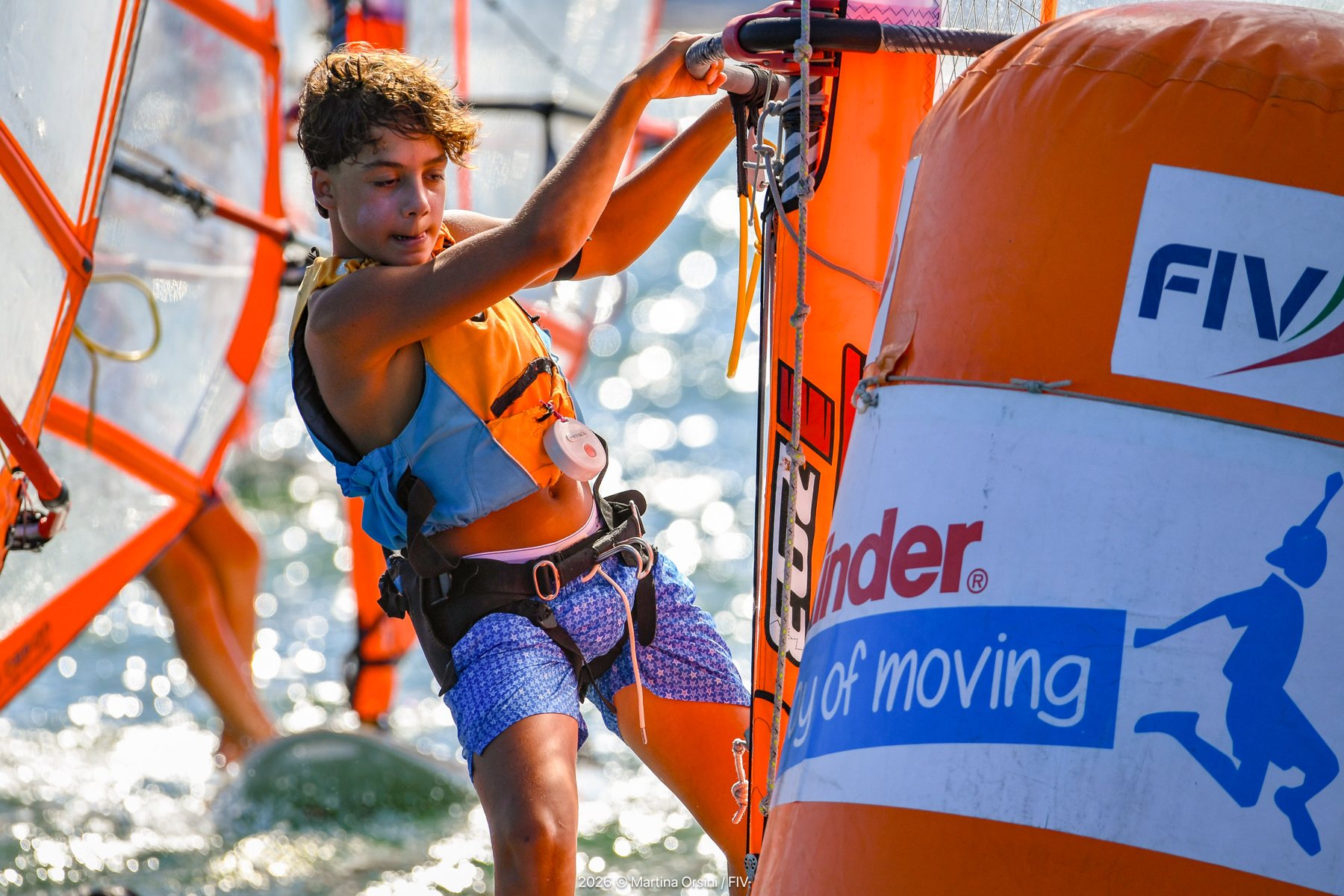 Giovane windsurfista che gira attorno a una boa arancione