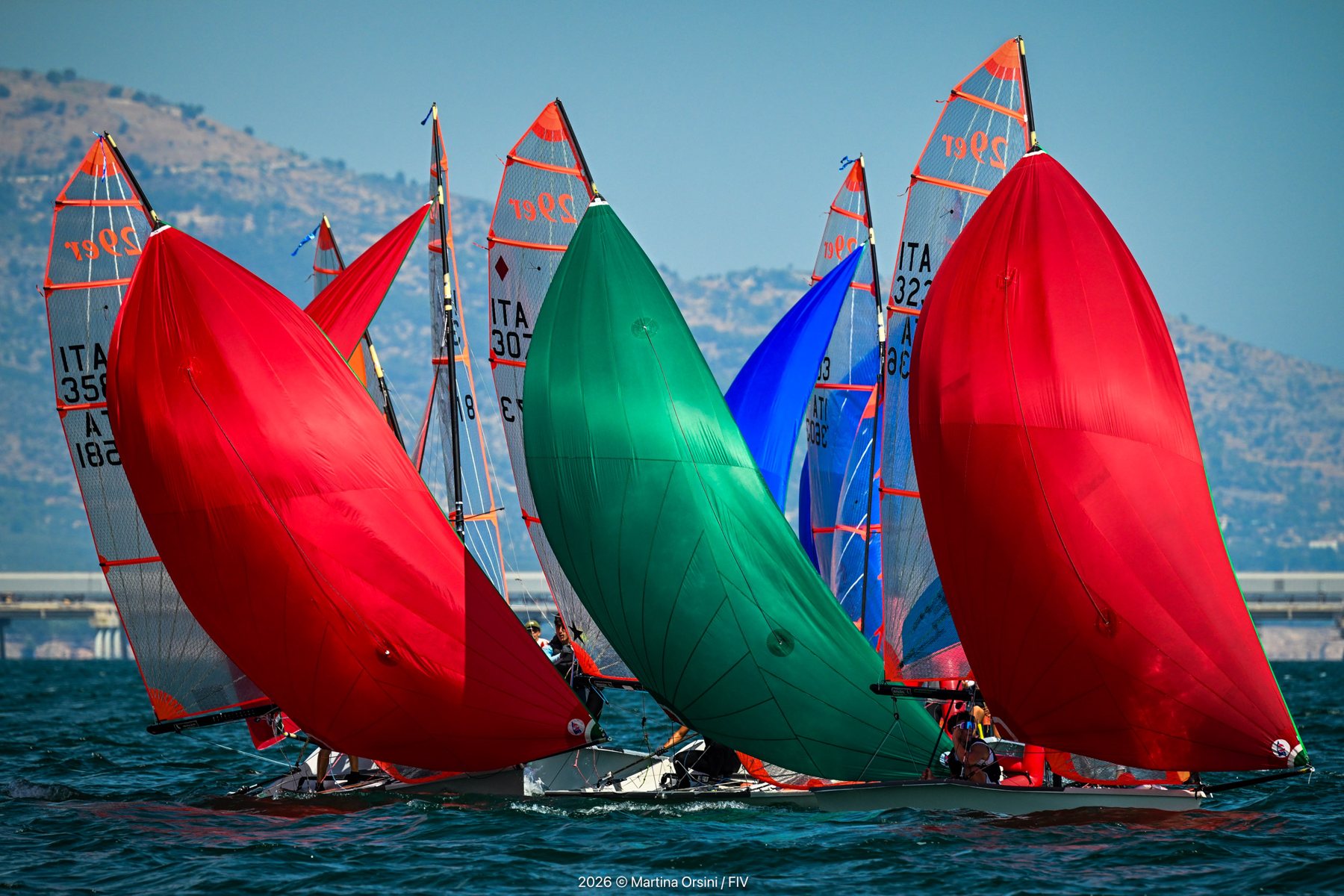 Derive con spinnaker rosso, verde e blu che si incrociano in regata