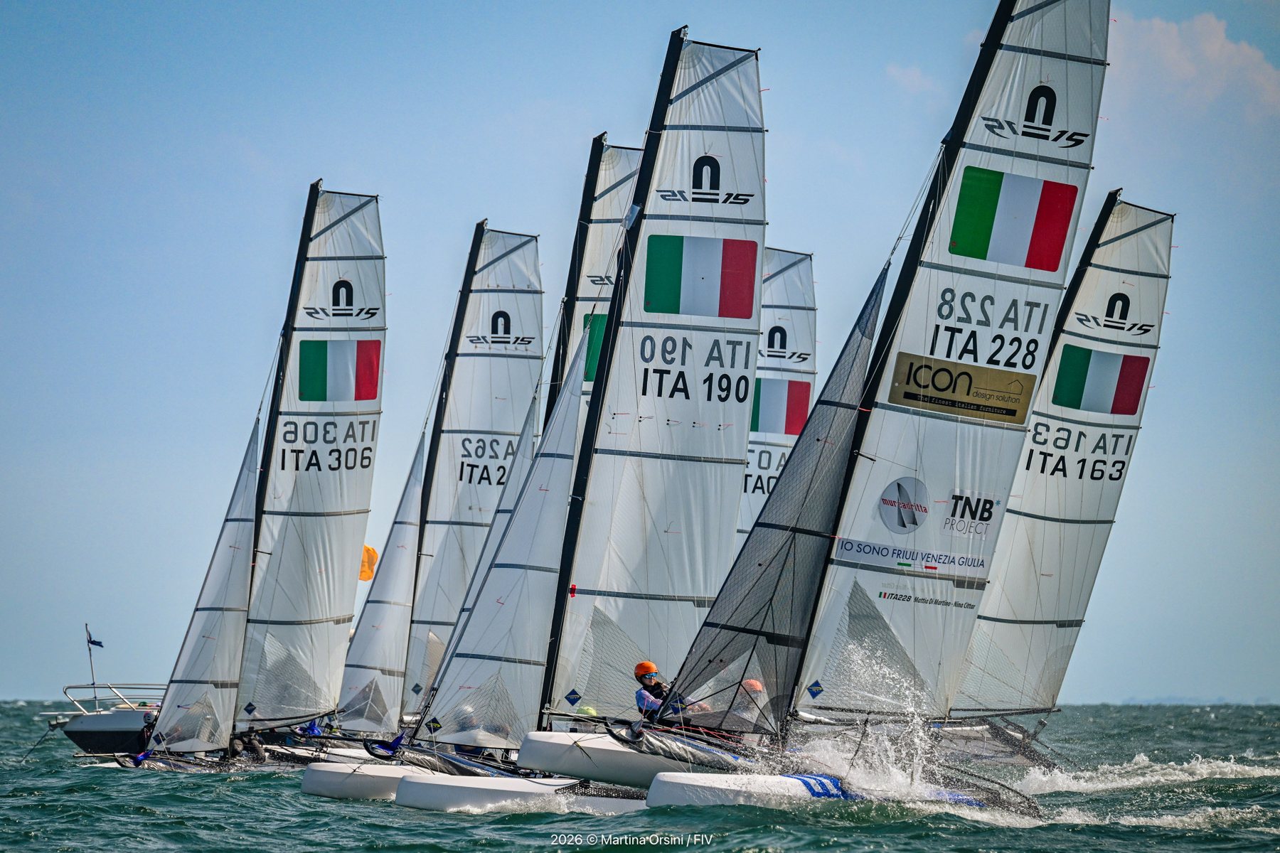 Gruppo di catamarani con le bandiere italiane sulle vele in partenza