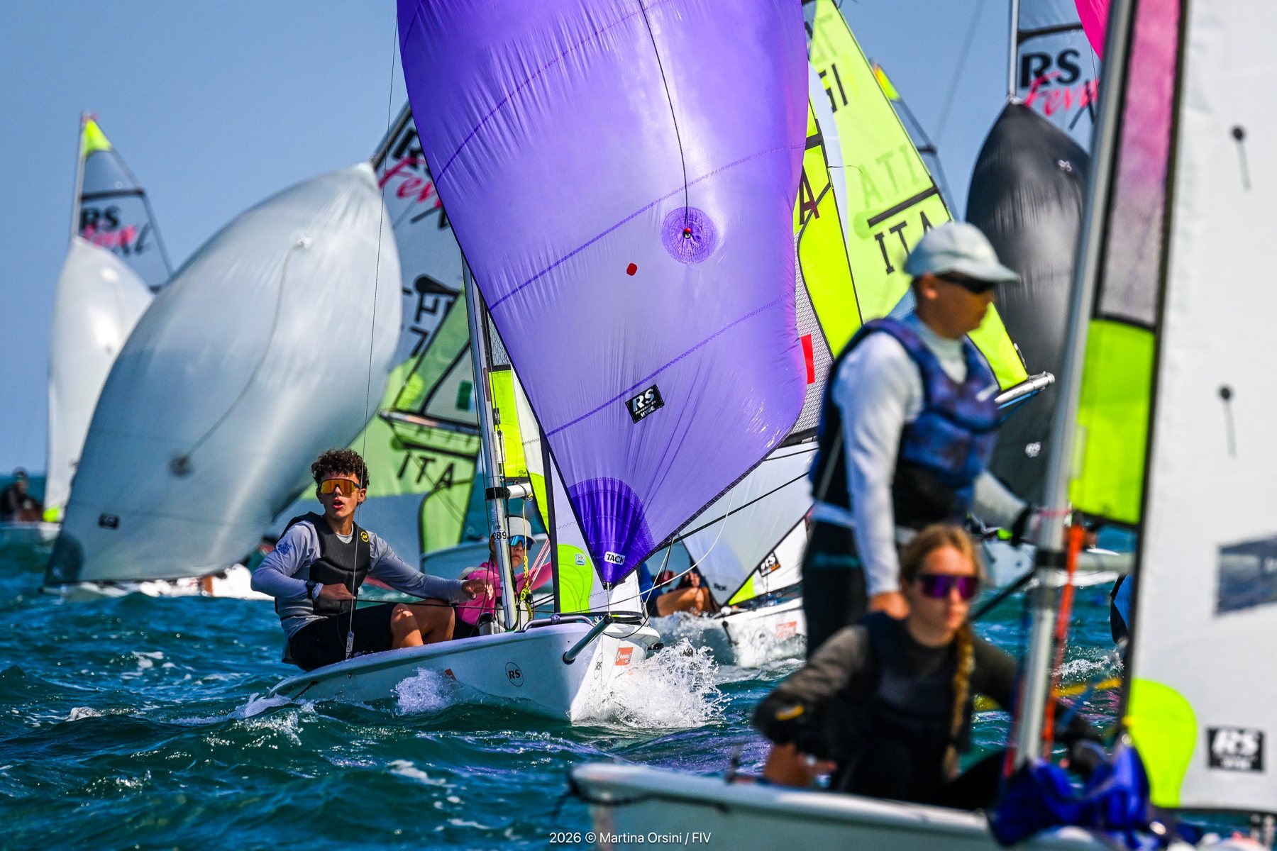Giovani equipaggi su derive con spinnaker viola e bianco durante la regata